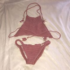 two pieces of pink crochet swimsuit laying on top of a white sheet