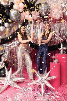 two women standing in front of balloons and confetti