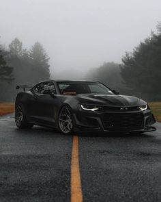 the chevrolet camaro zr1 is driving on a foggy road with trees in the background