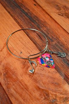 a colorful bracelet with a musical note charm on it sitting on a wooden table next to a pair of scissors