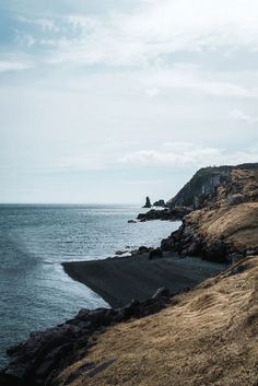 an ocean view with rocks and grass on the shore