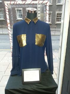 a blue shirt with gold sequins is on display in front of a building