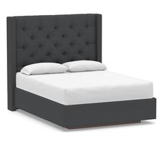 a bed with a black headboard and white pillows