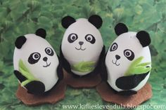 three stuffed panda bears sitting on top of each other in front of green leaves and plants