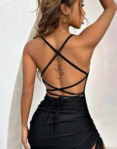 the back of a woman's body wearing a black dress with cross - over straps