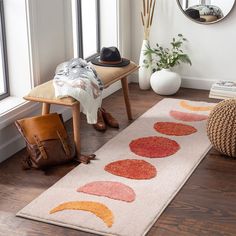 a white rug with red and orange circles on it next to a chair, mirror and purse