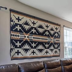 a living room with leather couches and a large navajo rug hanging on the wall