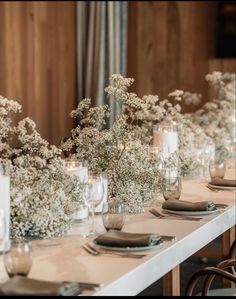 the table is set with candles and vases filled with baby's breath flowers