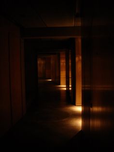 an empty dark hallway with light coming in from the ceiling and on to the walls