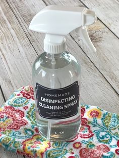 a bottle of disinfecting cleaning spray sitting on top of a colorful cloth