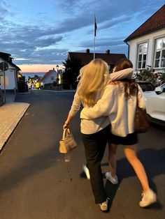 two women are walking down the street with their arms around each other as they hold hands