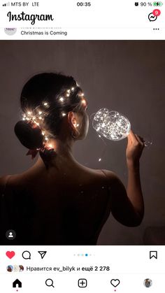 a woman with lights on her head holding a glass ball in front of her face