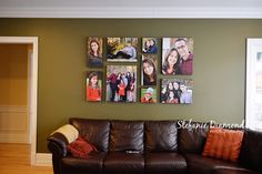 a brown leather couch sitting in front of a green wall with pictures hanging on it