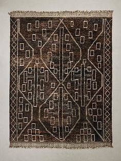 an old rug is hanging on the wall, with fringes around it and square shapes