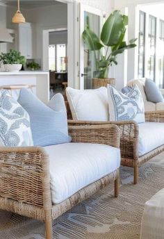 wicker couches with blue and white pillows on them in a living room area