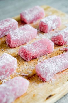 some food that is sitting on a wooden cutting board with powdered sugar over it