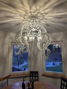 a dining room table with chairs and a chandelier hanging from the ceiling over it