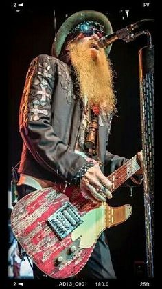 a bearded man with long hair playing an electric guitar