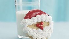 a cookie in the shape of santa claus next to a glass of milk