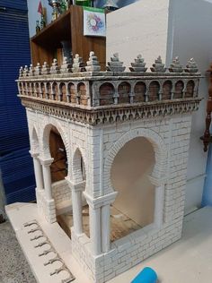 a model of a building made out of white bricks on a table next to a blue object