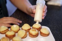 a person pouring milk on some small pastries