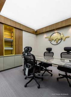 an office with black chairs and a glass table in front of the wall that has gold fish on it