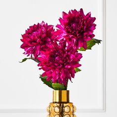 purple flowers in a gold vase on a table