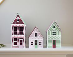 three paper houses sitting on top of a shelf