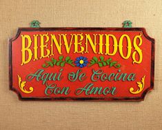 a sign that is on the wall in front of a door with spanish writing and flowers