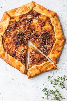 a pizza that has been cut into pieces and is sitting on a table next to some herbs