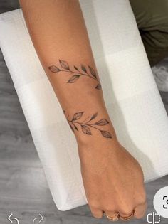 a woman's foot with a tattoo on her left arm and leaves on it