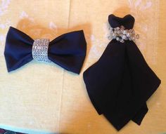 two black bow ties with crystal brooches on them sitting on top of a table