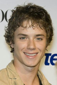 a young man with curly hair smiling at the camera