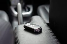 a cell phone sitting on top of a black leather seat in a car or truck