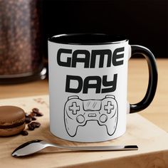 a coffee mug that says game day on it next to a spoon and cupcake