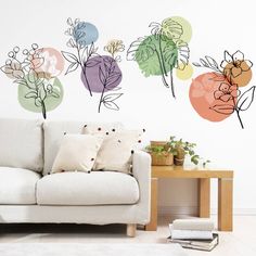 a white couch sitting in front of a wall with colorful flowers on it's side