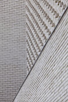 the side of a white brick building with a clock on it's face and an arrow pointing to the left