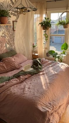 an unmade bed in a bedroom with plants on the window sill above it