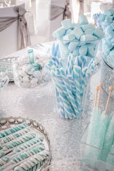 blue and white candy canes in clear glass vases on a silver table cloth