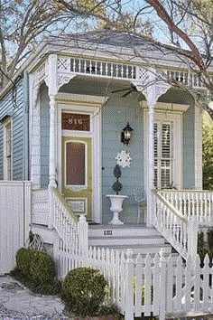 a blue house with white picket fence around it and a light on the front door