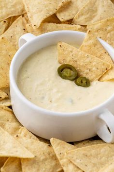 a white bowl filled with dip surrounded by tortilla chips