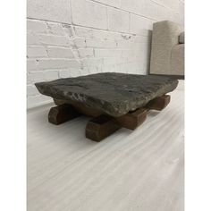 a stone table sitting on top of a wooden bench next to a white brick wall