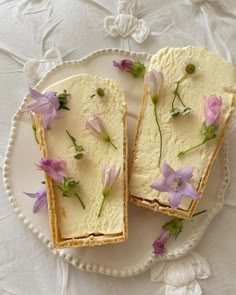 two pieces of cake on a plate with purple flowers and leaves scattered around the edges