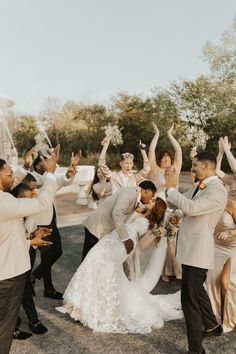 a bride and groom are surrounded by their wedding party in front of an outdoor fountain