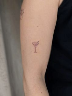 a woman's arm with a small martini tattoo on the left side of her arm