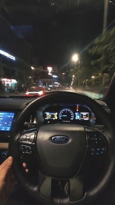 a person driving a car at night with the dashboard illuminated by street lights in the background