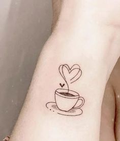 a small tattoo on the wrist of a woman with a cup of coffee in it