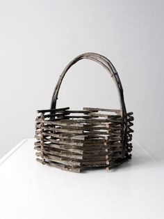 a basket made out of wooden sticks sitting on top of a white table next to a wall