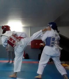 two people are practicing karate in an indoor area with blue mats and red mats on the floor