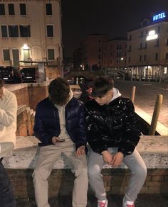 three people sitting on a ledge outside at night